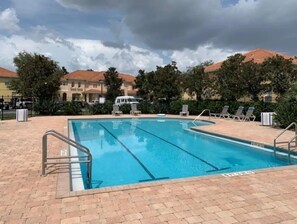 Relax by the pool surrounded by lush trees and buildings.