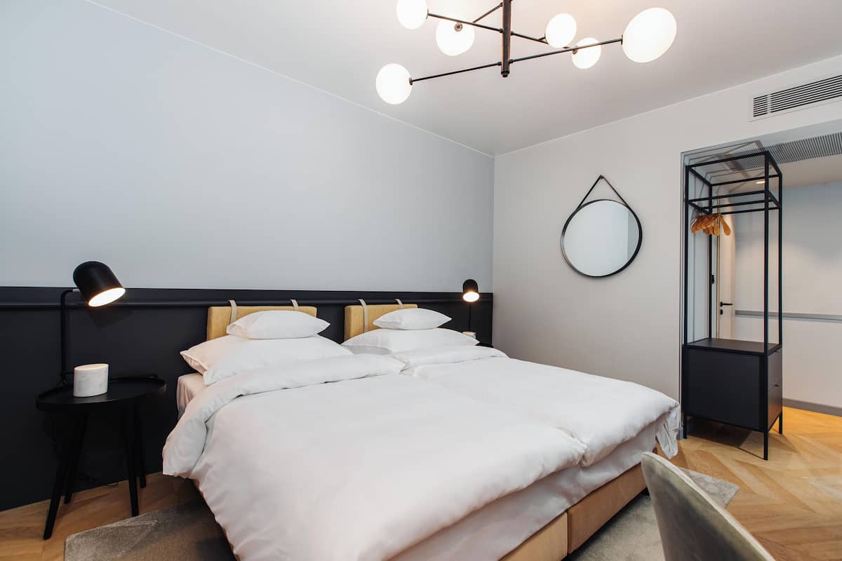 Un dormitorio moderno con una cama grande, mesitas de noche, una lámpara colgante, un espejo y un armario empotrado.