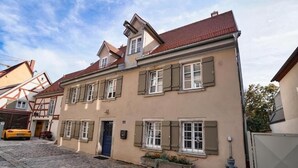 A two-story building with a red-tiled roof, a blue door, and a stone-paved courtyard. - RefuKium 'Alte Brennerei' in the center of Weißenburg (Weißenburg in Bayern)