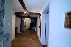 Un couloir doté d’un sol en pierre, de poutres en bois et d’un ventilateur de plafond.