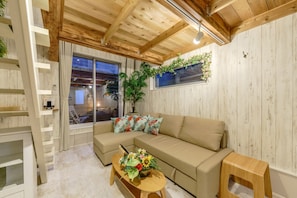 Relax in a comfortable seating area with a large sofa and coffee table, surrounded by a wooden ladder and shelving unit.