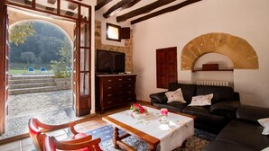 A cozy living room with a stone fireplace, a television, and a comfortable sofa. - Finca Morro, in a quiet location, views of the mountains, pool, WIFI, A/C (Pollenca)