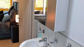 Un baño moderno con un lavamanos blanco, un espejo y un perchero para toallas.