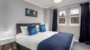A modern bedroom with a bed, a nightstand, a lamp, and artwork on the wall.