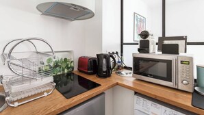 A kitchenette with a microwave, toaster, kettle, and a coffee maker on a wooden countertop. - Newly Renovated, Modern Studio Flat in Montmartre (Paris)