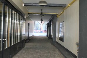 Un pasillo con suelo de baldosas, un ventilador de techo y una puerta a la derecha.