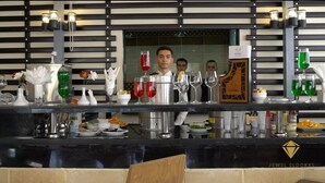 Una zona de bar con diseño moderno, que presenta una encimera negra, diferentes tipos de vasos y un cartel que dice "JEWEL ELDOKKI".