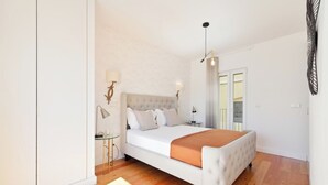 A bedroom with a bed, bedside tables, a lamp, and a view of the outside.