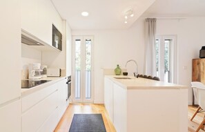 A modern kitchen with white cabinetry, a built-in oven, a coffee maker, and a sink.
