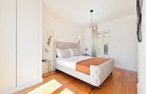 A bedroom with a bed, bedside tables, a lamp, and a view of the outside.