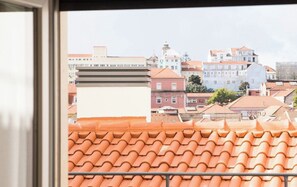 Vista de tejados de teja anaranjada y una variedad de edificios, incluyendo una iglesia con cúpula y un edificio blanco con un reloj.