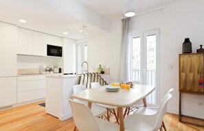 A modern kitchen with white cabinetry, a microwave, and a dining area with a table set for four.