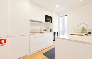 A modern kitchen with white cabinets, a microwave, a coffee maker, and a sink with a green vase.
