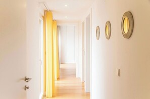 A hallway with a wooden floor, white walls, and a yellow curtain.