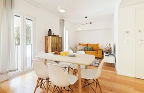 Un salón luminoso con una mesa de comedor, sillas, un sofá y una televisión.
