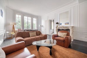 A spacious living room with a large sofa, a glass coffee table, and a fireplace.