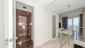 A modern hotel room with a balcony, a shower area, and a bed. - Belussi Exclusive Suites - Adults Only (Zakynthos)