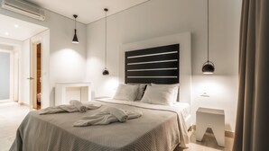 A modern bedroom with a large bed, bedside tables, a headboard with horizontal lines, and pendant lighting. - Belussi Exclusive Suites - Adults Only (Zakynthos)