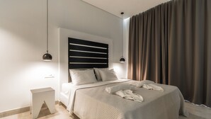 A modern bedroom with a bed, bedside tables, and a headboard with horizontal slats. - Belussi Exclusive Suites - Adults Only (Zakynthos)