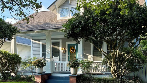 A two-story house with a covered porch, a front door with a flower wreath, and a brick pathway leading to the entrance. - Ann St Cottage In The Heart Of Historic Beaufort (Beaufort)