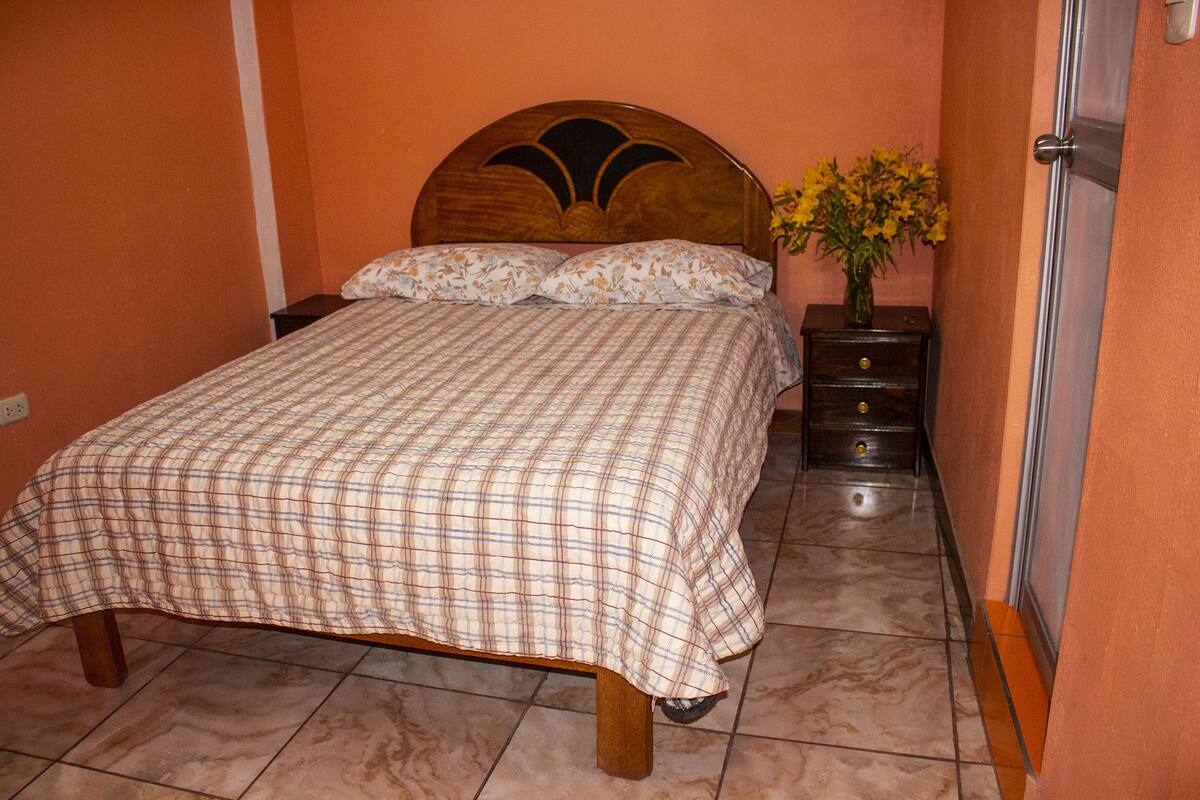 Ein Schlafzimmer mit einem Bett, einem Nachttisch und einer Vase mit Blumen.
