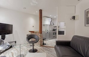 A modern living room with a flat-screen TV, a leather sofa, and a glass coffee table.