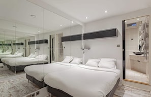 A modern bedroom with a large bed, a glass partition, and a bathroom with a sink and towel rack. - The Modern Eiffel 2BDR Stay in Paris Center (Paris)
