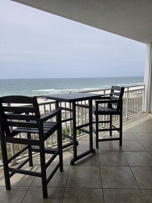 A balcony with a view of the ocean, two chairs, and a table. - Delightfully Spacious Gulf Front Beauty.... (Pensacola)