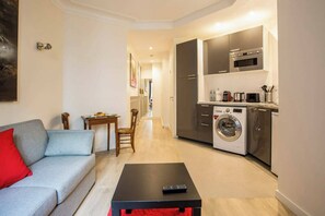 A compact living space with a sofa, a coffee table, a dining area, and a kitchenette with a washing machine. - Beau 2 Pieces Artiste near Saint Germain (Paris)