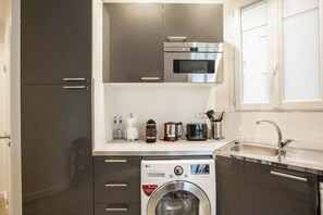 A compact kitchen with a built-in washing machine, a microwave, and a sink. - Beau 2 Pieces Artiste near Saint Germain (Paris)
