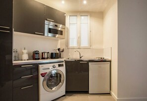 A compact kitchen with a built-in washer, a dishwasher, and a microwave. - Beau 2 Pieces Artiste near Saint Germain (Paris)