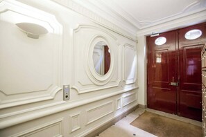Un couloir avec un mur blanc, une porte dotée d’un miroir et une serrure à clavier.