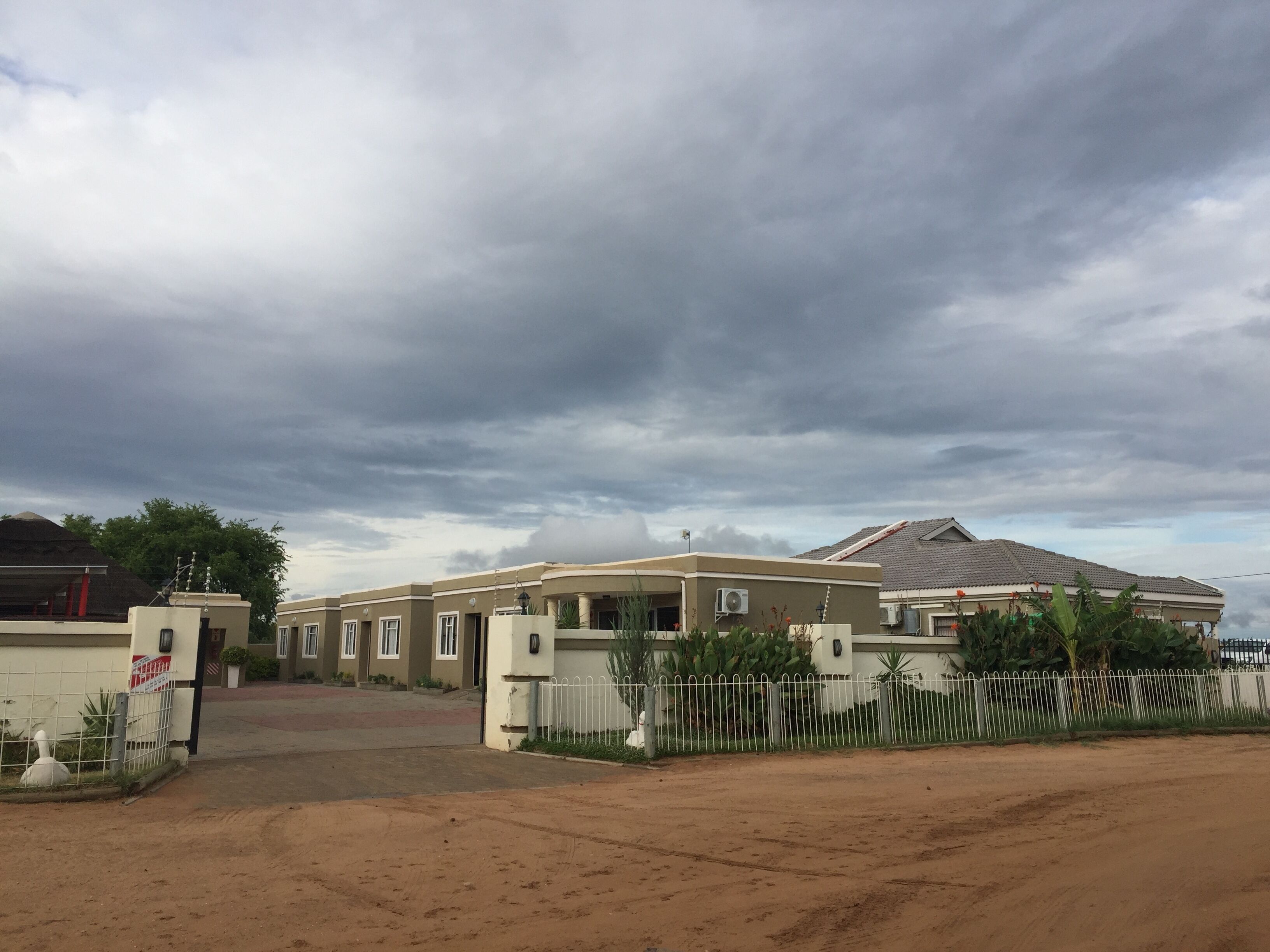 A residential area with a house featuring a gated entrance, a driveway, and a large mountain in the background.