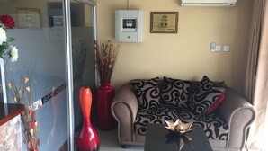 Ein Wohnzimmer mit einer Couch, einem Couchtisch, einer roten Vase und einer Wand-Klimaanlage.