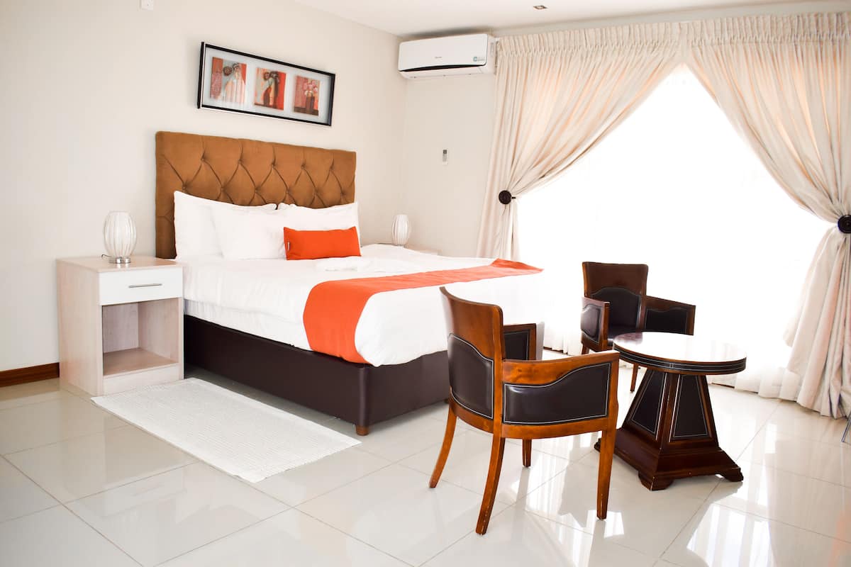 A hotel room with a bed, bedside table, chair, and a small round table.