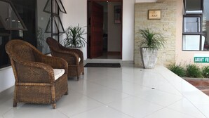 A reception area with wicker chairs, a large potted plant, and a sign indicating 'LIGHT VENT'. - Royal Court Guest House (Letlhakane)