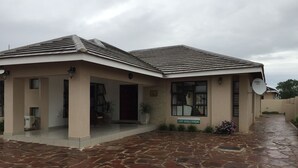 A building with a stone-paved entrance, a covered porch, and a sign indicating light vehicle parking. - Royal Court Guest House (Letlhakane)