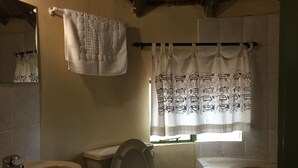 Une salle de bain avec des toilettes, un lavabo et une baignoire. Une serviette est accrochée à un porte-serviettes et il y a un rideau de douche à motifs.