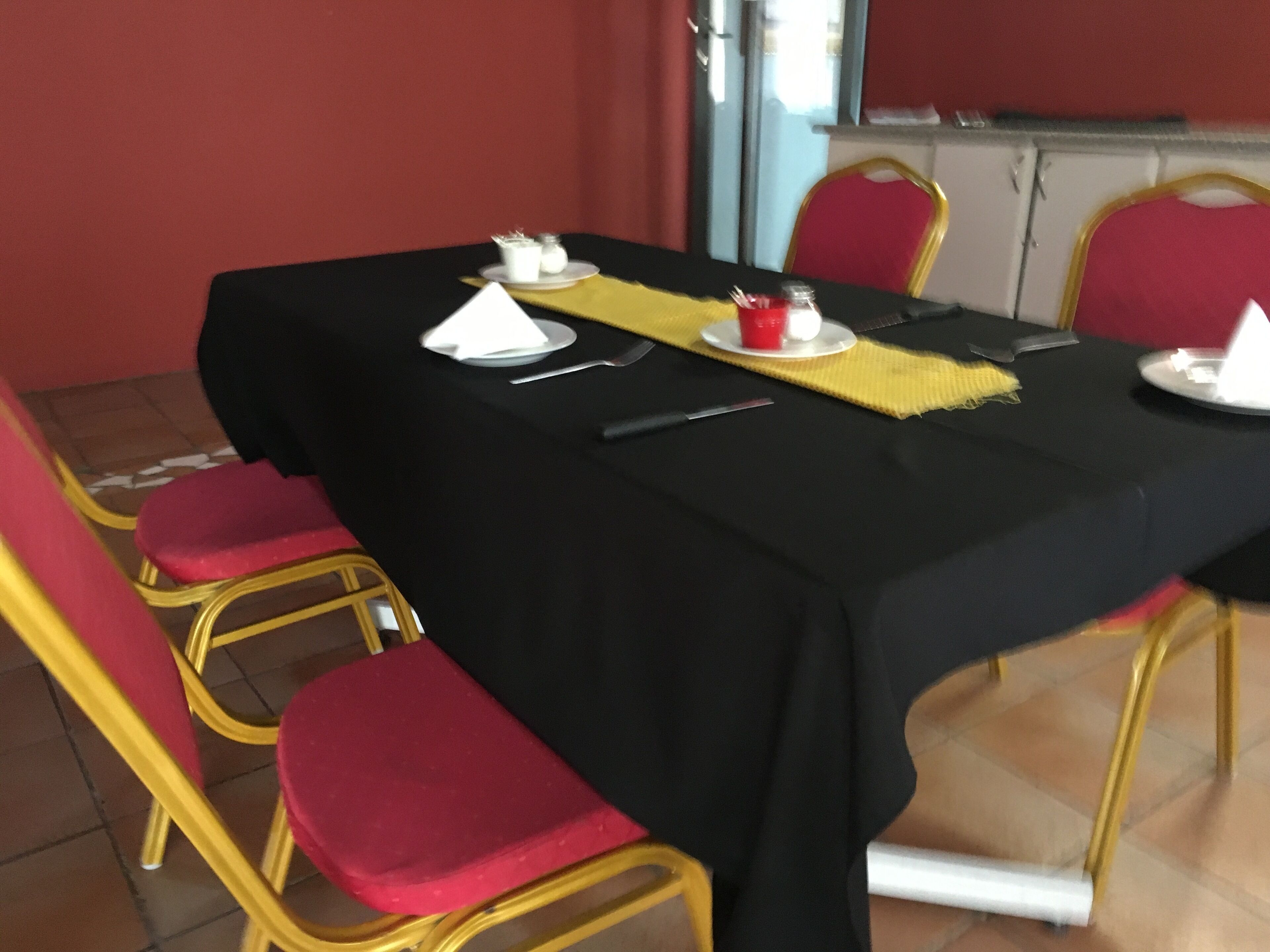 A dining table set with a black tablecloth, red chairs, and a yellow placemat.