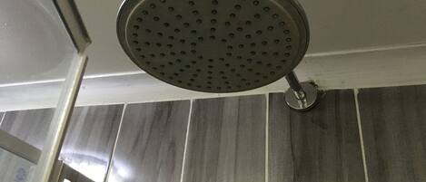 A showerhead with a circular design and multiple holes, mounted on a wall with a tiled surface.