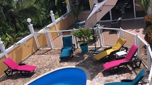 A swimming pool with lounge chairs and a stone-tiled deck.