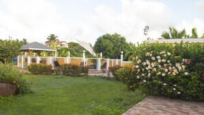 A garden with a gazebo, a tiled patio, and a variety of flowering plants.