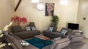 A modern living room with grey sofas, a coffee table, and decorative plants.