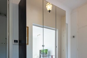 Une salle de bain moderne avec une douche à parois de verre, un téléviseur bien en évidence et un luminaire fixé au mur.
