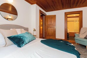 Une chambre à coucher avec un lit, une porte en bois et un luminaire fixé au mur.