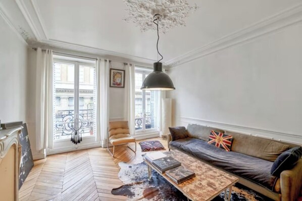 A living room with a sofa, a coffee table, a chair, and a hanging light fixture.