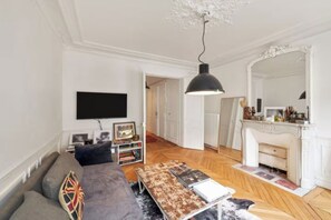 A living room with a sofa, a coffee table, a fireplace, a television, and a bookshelf.