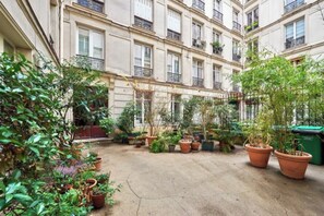 A courtyard with potted plants and a building with multiple balconies. - Cosy flat for 2 people near Pigalle (Paris)
