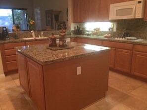 A kitchen with granite countertops, wooden cabinets, and a built-in microwave.