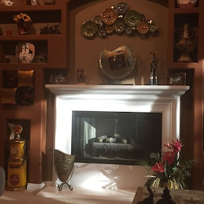 A fireplace with a mantel decorated with various items, including a clock and a framed picture.